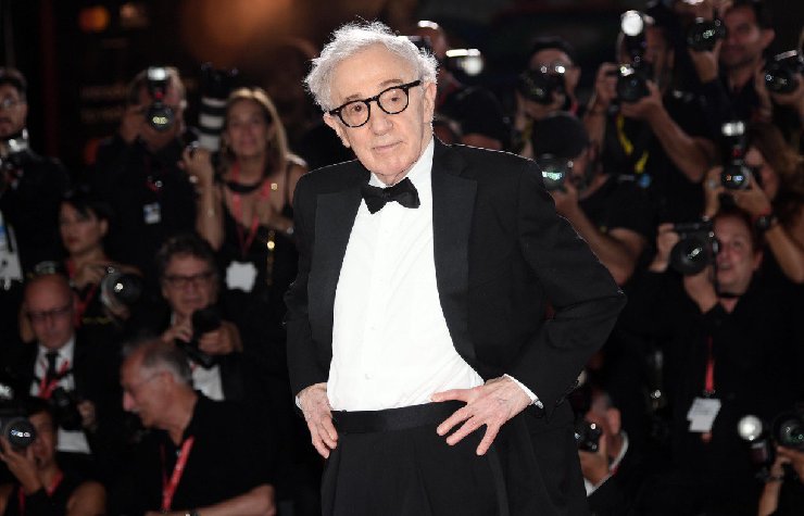 Woody Allen in giacca e papillon in un red carpet con le mani sui fianchi